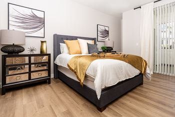 A bedroom with a bed, nightstand, and artwork on the wall.